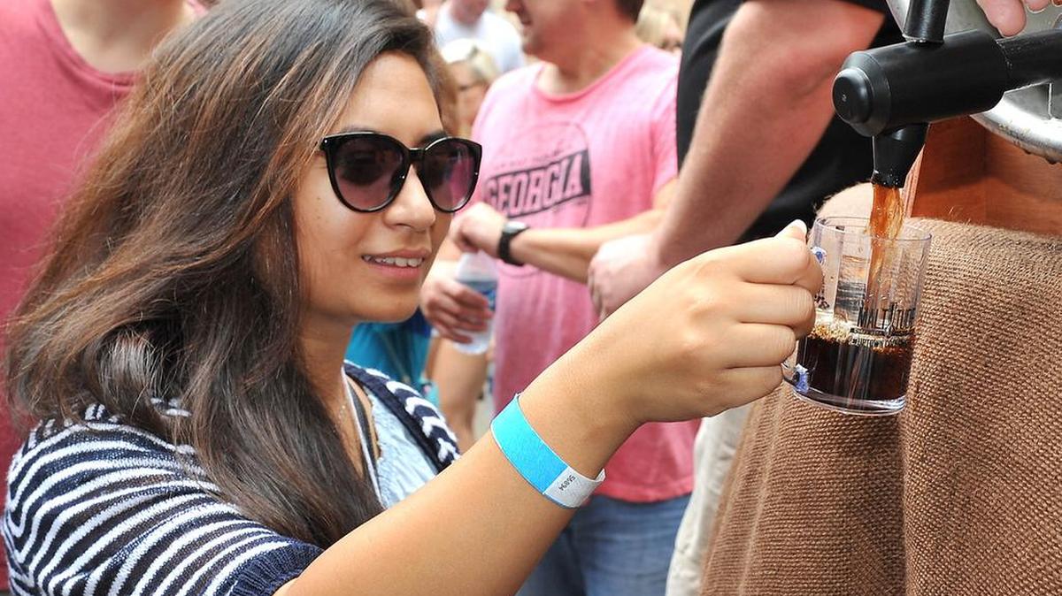 Asmita Piya is one of the first to try a sample from the Beer Keg from the Omaha Brewing company tapped for the 2015 Uptown Beer and Wine Festival.