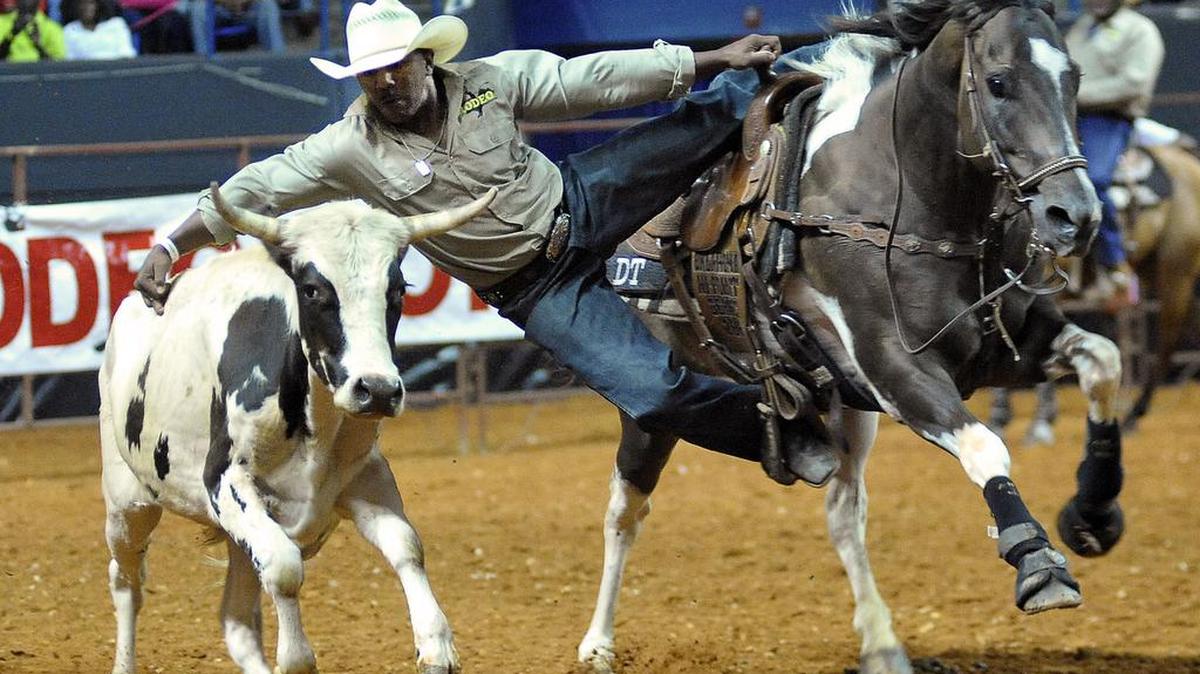 Danelle Tipton moves from his horse to wrestle the steer to the ground during the first Annual Columbus Black Rodeo on July 25, 2015.