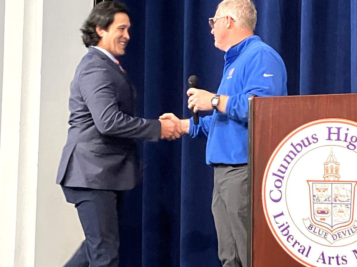 Robert “Bob” Peters shakes hands with Columbus High School athletics director Chad Mathis in the CHS auditorium Jan. 31, 2024, after Mathis announced Peters has been promoted from offensive coordinator to head coach of the football team.