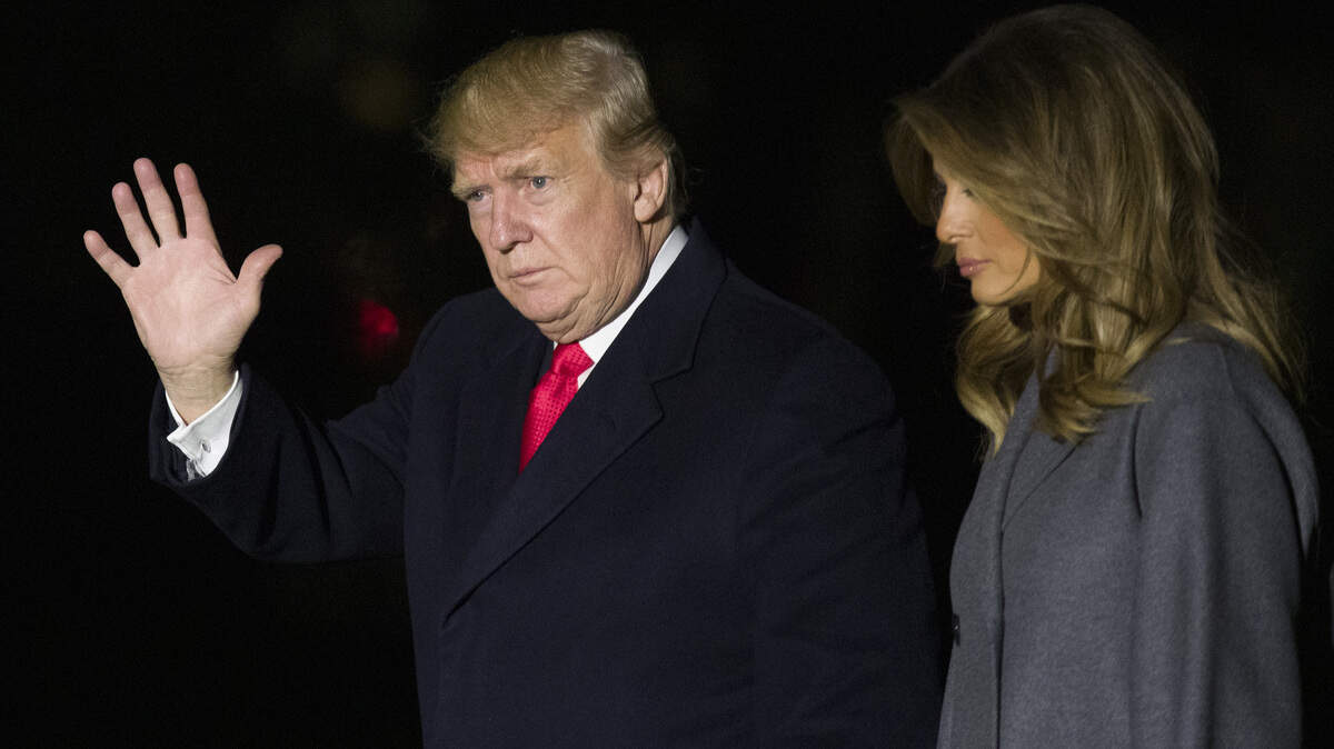 President Donald Trump waves as he walks with first lady Melania Trump, after stepping off Marine One, on the South Lawn of the White House on Sunday in Washington. Trump was returning from a trip to Paris.