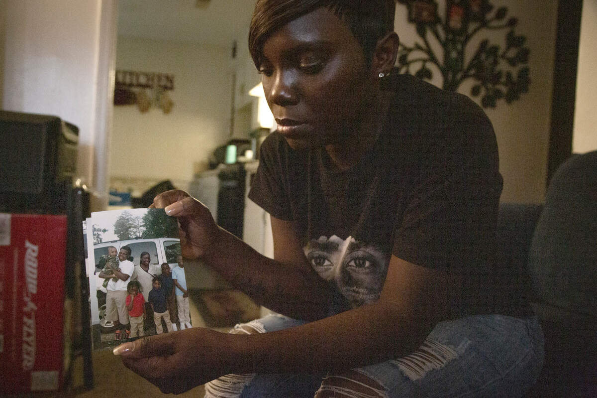 Tiffany Richardson holds a family photo at her home in Columbus, Ga. on Aug. 19, 2021. Her son Cortez Richardson, in the white shirt, was shot in a random act of gun violence while they were driving home on Aug. 13.