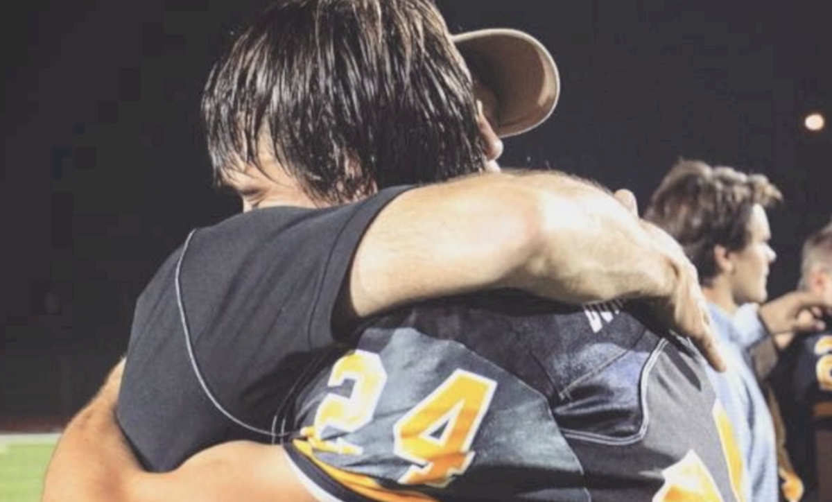 Graham Durham (pictured in jersey) hugs father Danny Durham after a Harris County High School football game.