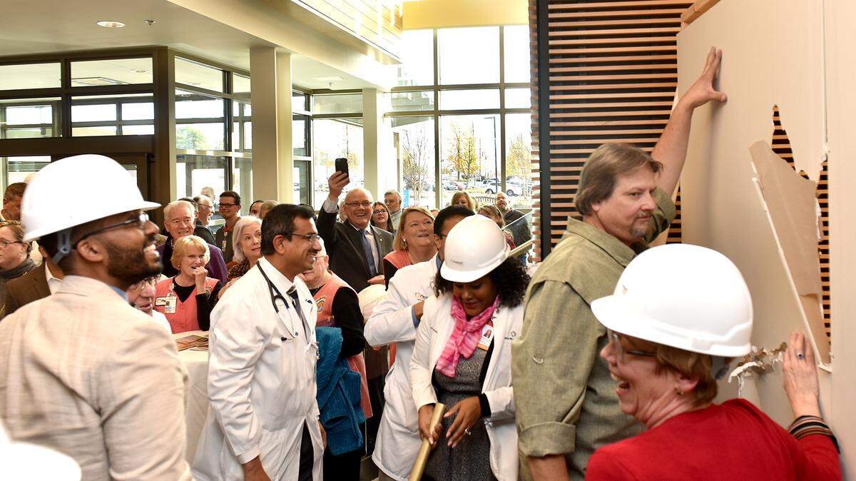 Guests and staff members take turns swinging a golden hammer at the temporary wall to symbolize the expansion of the John B. Amos Cancer Center. The event marked the completion of Phase 1 of the expansion of the cancer center, including the addition of a 48,000 square-foot adjoining building. The celebration also helped launch a capital campaign for the John B. Amos Cancer Center to raise funds to renovate the current facility and also invest in next-generation technology.