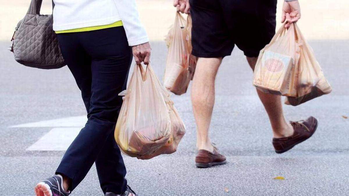 Pedestrians crossing street holding plastic bags of groceries