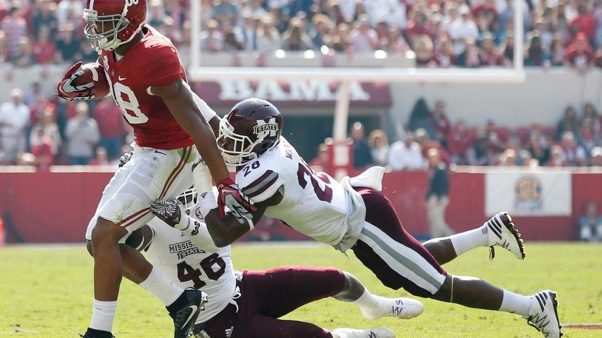 Alabama tight end O.J. Howard, right, drags Mississippi State linebacker Dezmond Harris, center, and linebacker DeAndre Ward during a tackle Saturday in Tuscaloosa, Ala.