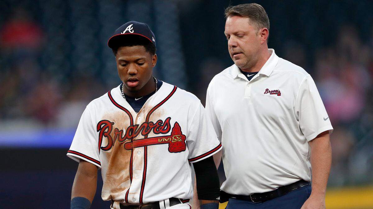 Atlanta Braves’ Ronald Acuna Jr. leaves the field with a training staff member in the second inning of a baseball game after being hit by a pitch from Miami Marlins starting pitcher Jose Urena in the first inning Wednesday, Aug. 15, 2018, in Atlanta