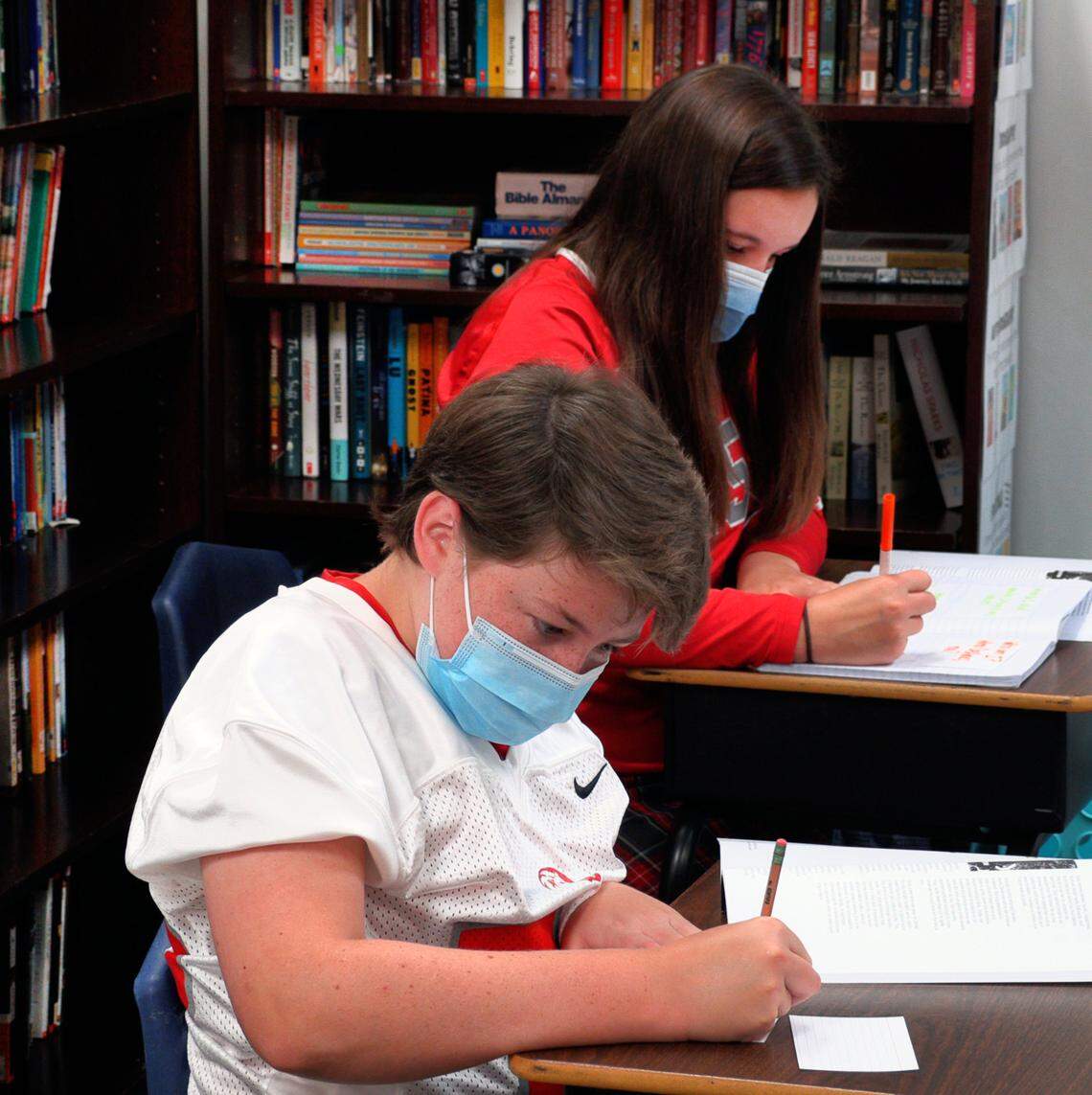 Wilson Walker, front, and Caroline Peak, eighth-graders at St. Luke School in Columbus, Georgia, work through a lesson in the Love Like Lexi workbook under the guidance of their homeroom teacher Anne Plott.