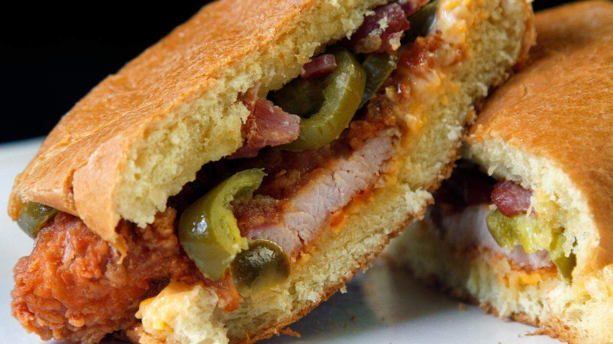 The Holy Grail Chicken Sandwich at The Chicken Lady’s Coop in Columbus, Georgia includes fried chicken, pimento cheese spread, bacon, and peach and jalapeno drizzle, all on a brioche bun. 05/20/2021