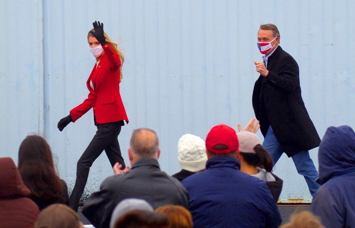 U.S. Senator Kelly Loeffler, left, and U.S. Senator David Perdue arrive Thursday at a rally at the Columbus airport in Columbus, Georgia.