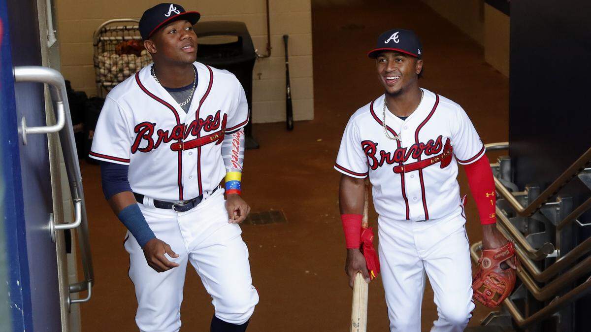 In this Saturday, May 5, 2018 photo, Atlanta Braves left fielder Ronald Acuna Jr., left, and second baseman Ozzie Albies (enter the dugout before a baseball game against the San Francisco Giants in Atlanta. Acuna and Albies are two of the youngest players in major League Baseball