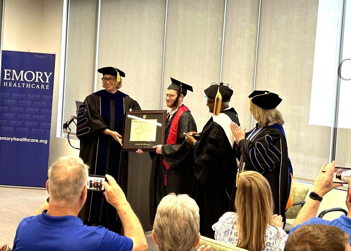 Columbus State University president Stuart Rayfield presents Grant Martin his diploma during the special graduation ceremony CSU conducted for him May 25, 2024, at Emory University Hospital in Atlanta, where he is waiting for a heart transplant.