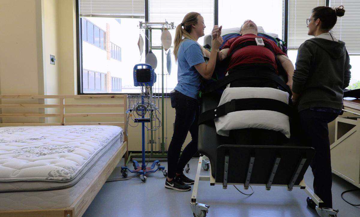 Occupational therapists Tayla Dockins and Jessica Taylor work Tuesday afternoon with Mark Jones at the Shepherd Center in Atlanta. Jones is at the Shepherd Center recovering from a spinal cord injury he sustained in an automobile accident.