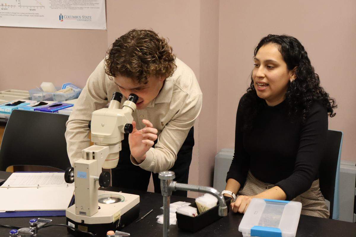 Senior biology students Adian Rush and Emily Marin examine samples of the ear bone of a fish to accurately date the fish’s age and plan to look at parasites in the lab at LeNoir Hall of CSU.