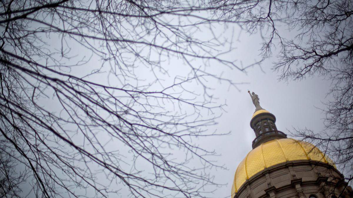In this file photo the dome of the Georgia State Capitol stands between tree branches in Atlanta.