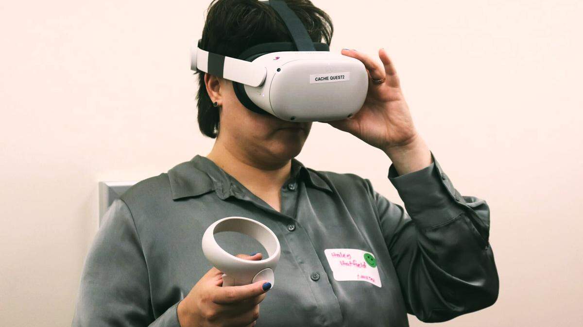Haley Hatfield, a Ph.D. candidate at UGA’s Grady School of Mass Communication and Journalism setting up the VR Meta Quest headset for the demo-mode of Weather the Storm at an Environmental Science conference in 2024.