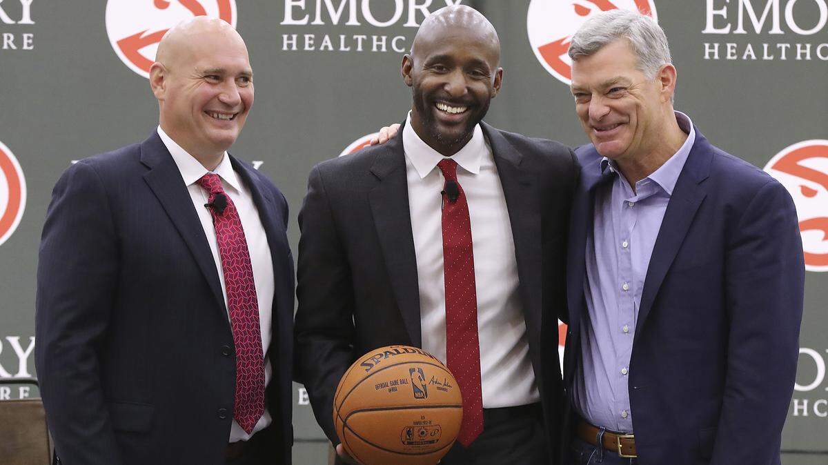 Atlanta Hawks general manager Travis Schlenk, left, and owner Tony Ressler, right,  introduce Lloyd Pierce, center, as the team's full-time coach Monday, May 14, 2018, in Atlanta. Pierce has been an assistant with the Philadelphia 76ers and the Memphis Grizzlies