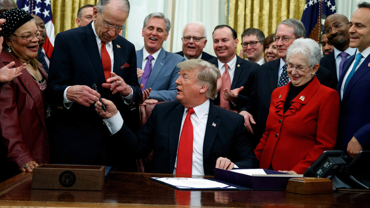 President Donald Trump hands a pen to Sen Chuck Grassley, R-Iowa, after signing criminal justice reform legislation in the Oval Office of the White House on Friday in Washington. Rep. Virginia Foxx, R-N.C, front row, second from right, watches.