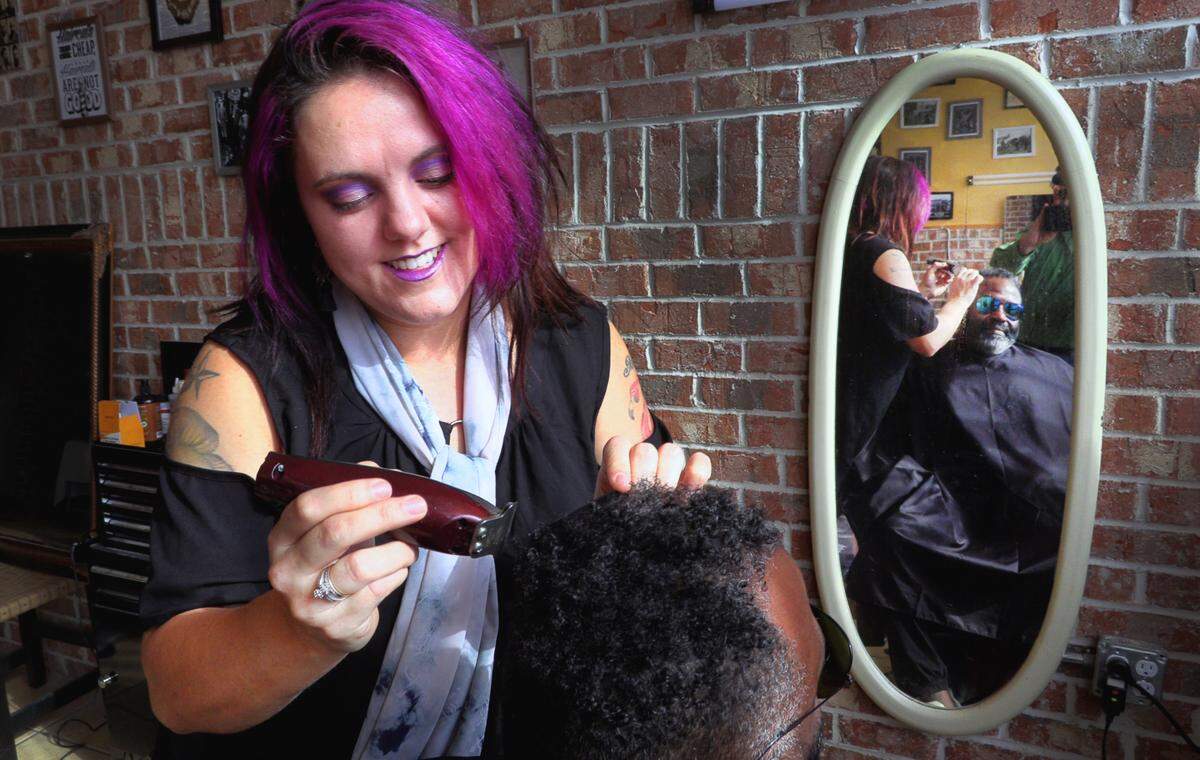 Christina Williams, owner of Barber Saloon and Giovanna’s Pizzaria and Restaurant in Phenix City, Alabama, touches up a customer’s hair Wednesday afternoon.