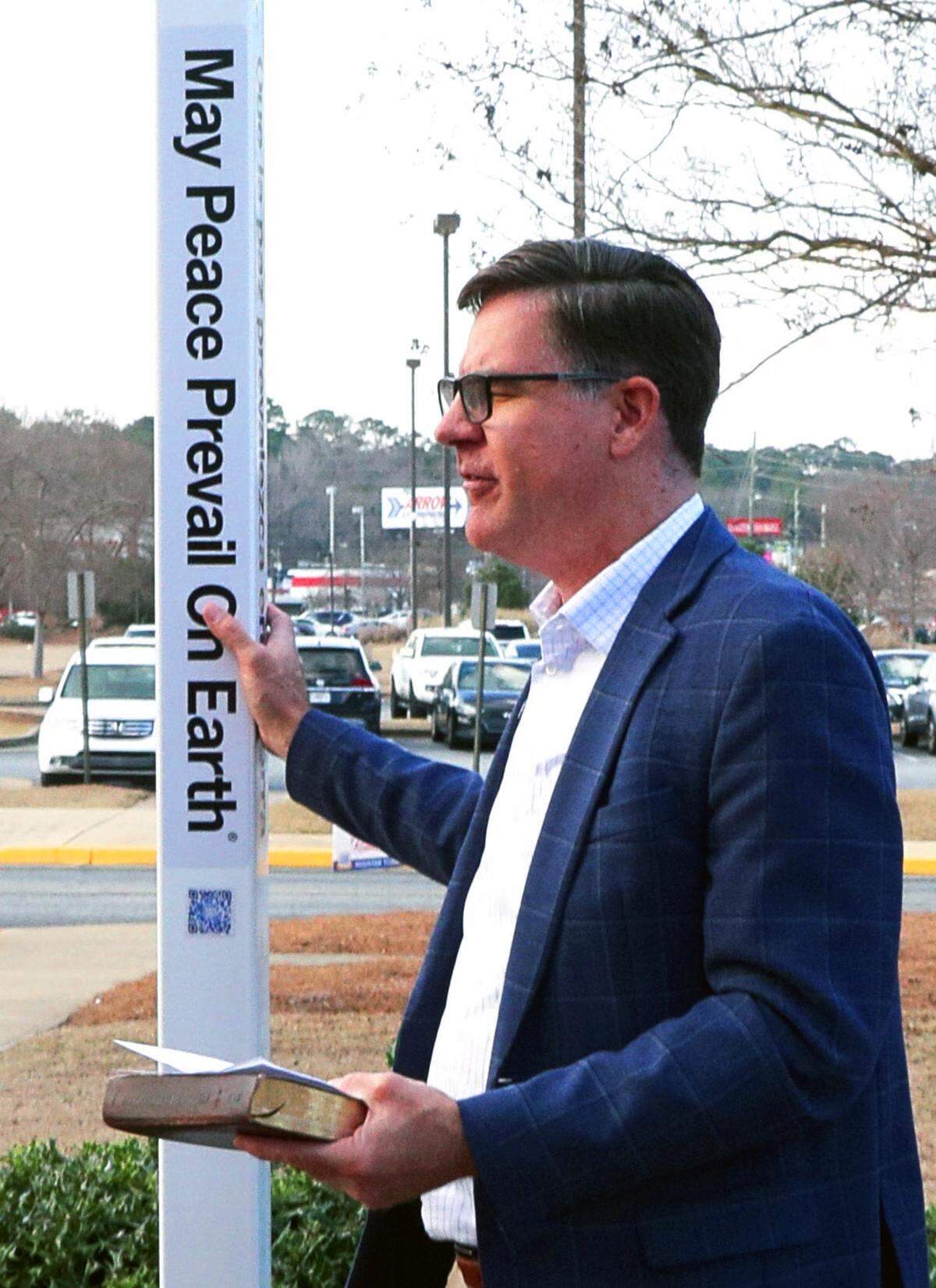 The Rev. Thad Haygood, senior pastor of St. Luke Church in Columbus, leads a prayer during the Peace Pole dedication ceremony conducted by the Rotary Club of Columbus on Feb. 19, 2026, at the Columbus Public Library. The Peace Pole is inscribed with messages of peace in four languages.