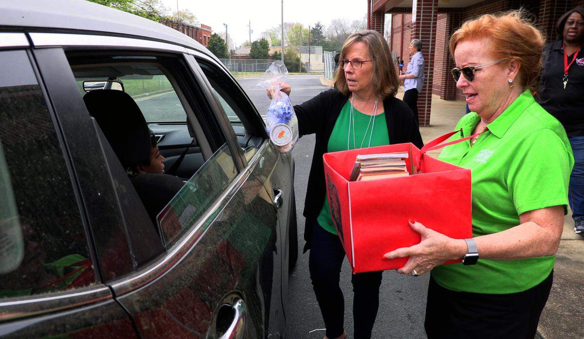 Karen Cook, left, and Marquette McKnight were among the volunteers helping distribute food and books to students at Fox Elementary School in Columbus, Georgia Tuesday morning, March 17, 2020. Volunteers helped distribute meals to school kids Tuesday at Fox Elementary School in Columbus, Georgia. They also gave them free books. It’s part of the Muscogee County School District’s effort to keep kids fed while school is out of session.