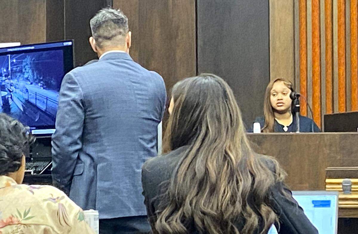 Defense attorney Allen Jones questions Tyteonna McAllister, the mother of defendant Homer Upshaw’s child. To her left is a screen showing surveillance video of a double-homicide scene at Wilson Homes.