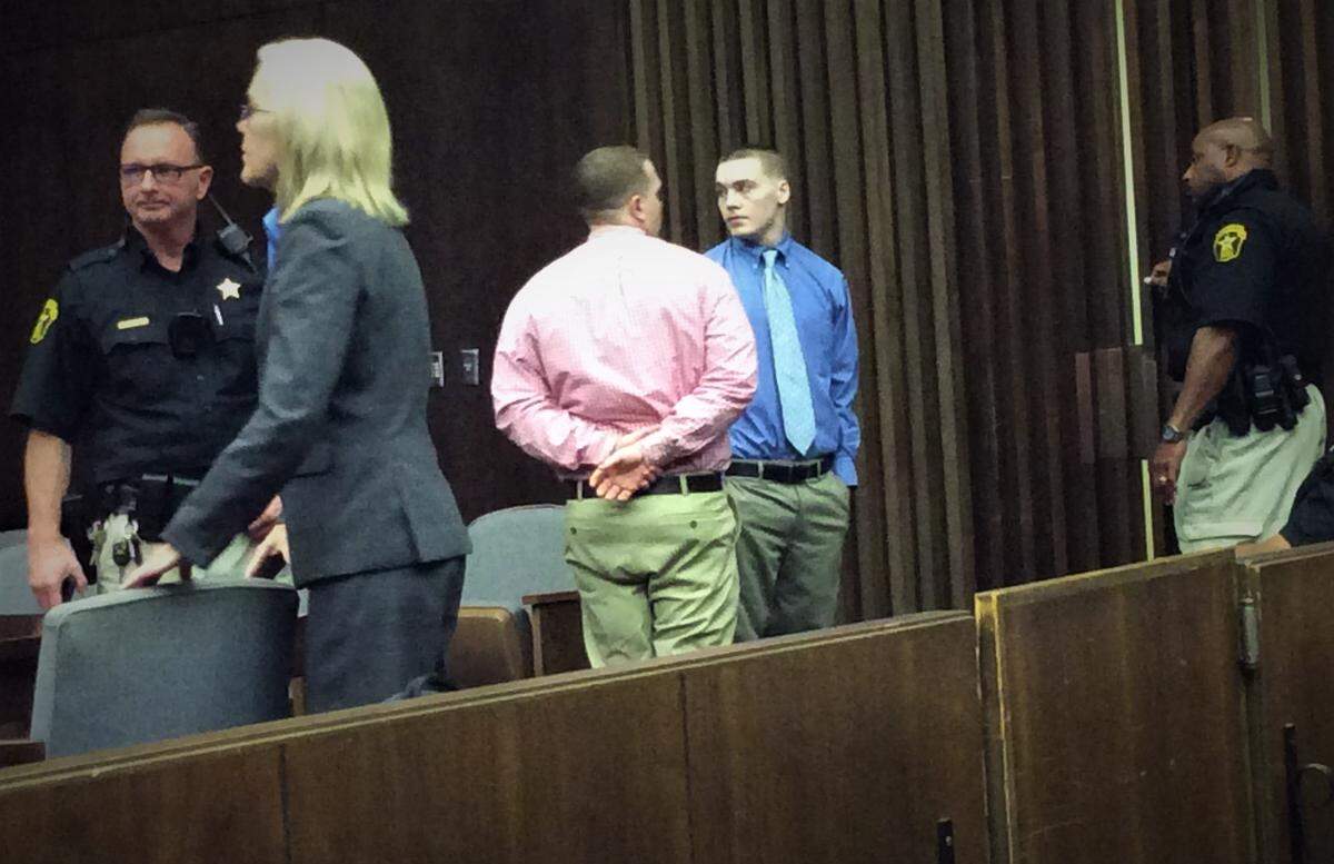 Thomas Meade (in pink shirt, center), and Andrew Scarborough (in blue shirt) leave court Tuesday during a break in closing arguments.