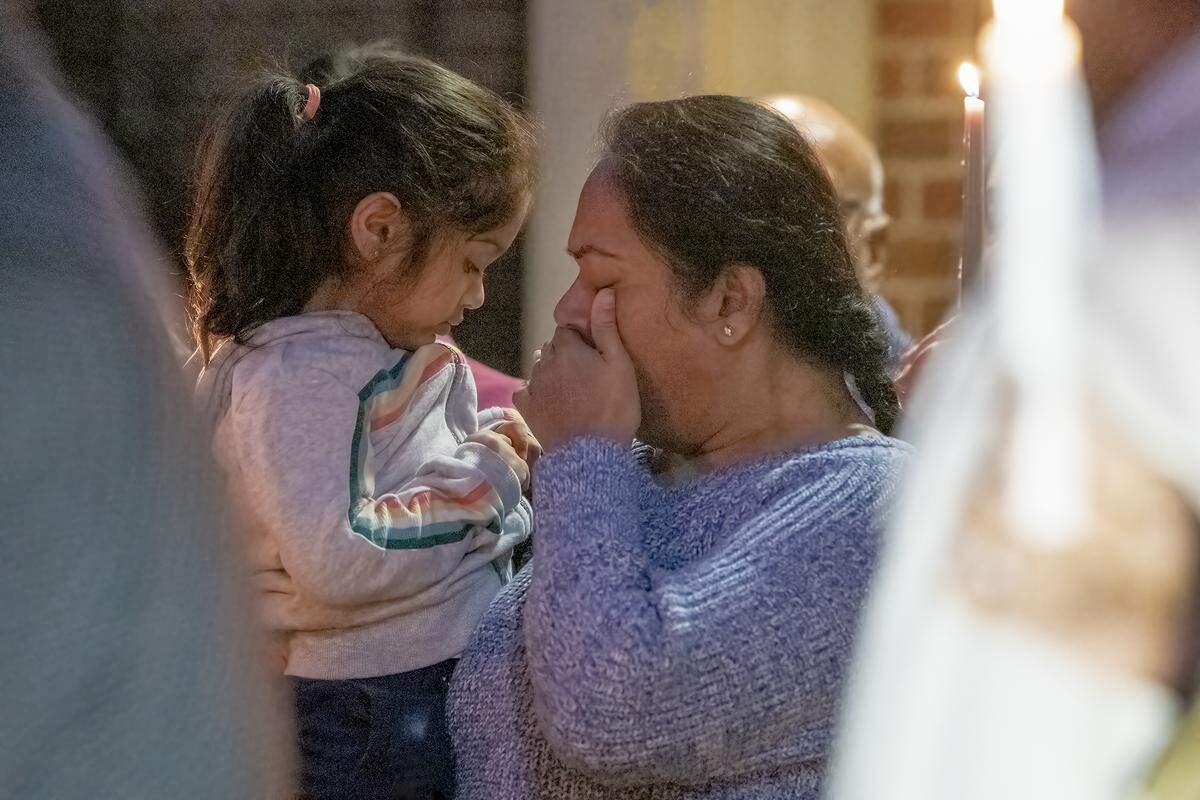 Roshni Patel holds her 3-year-old daughter during a candlelight vigil on Dec. 13, 2021, for her late husband, Amit Kumar Patel, outside the Synovus branch in Columbus, Georgia where Amit Patel was shot to death.