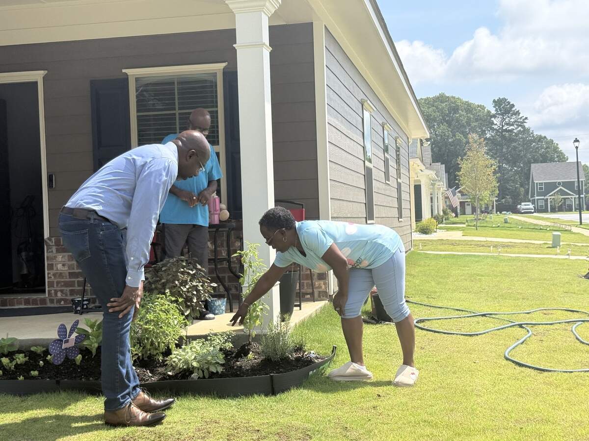 U.S. Sen. Raphael Warnock (D-Ga.) talks to Columbus residents about their garden during his July 6, 2026, tour of Elliott’s Walk and sites of upcoming housing developments in Columbus.