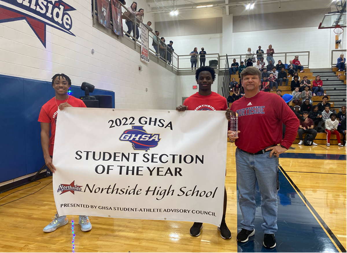 From left, Northside High School students Derrick Lockhart and Jyrine Stewart, along with athletics director Morgan Ingram, show the banner celebrating Northside’s victory in the 2022 Class A-5A Georgia High School Association Student Section Spirit Challenge.