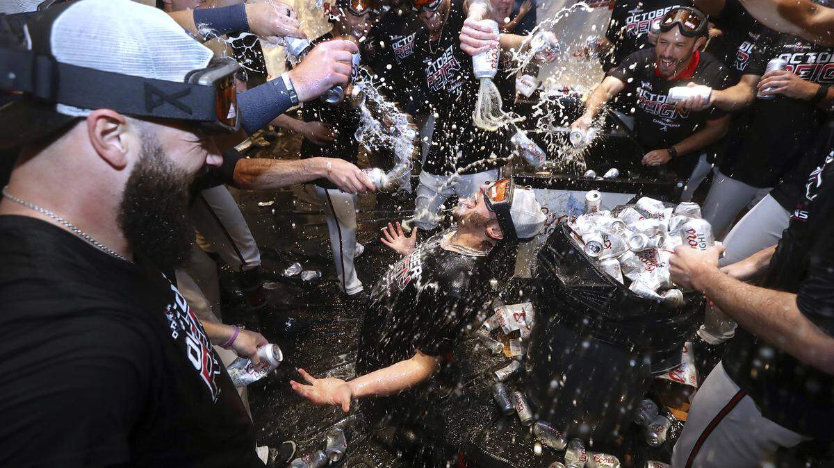 Atlanta Braves third baseman Josh Donaldson kneels on the floor and is doused by teammates while they celebrate after clinching the NL East baseball title with a victory over the San Francisco Giants, Friday, Sept. 20, 2019, in Atlanta.