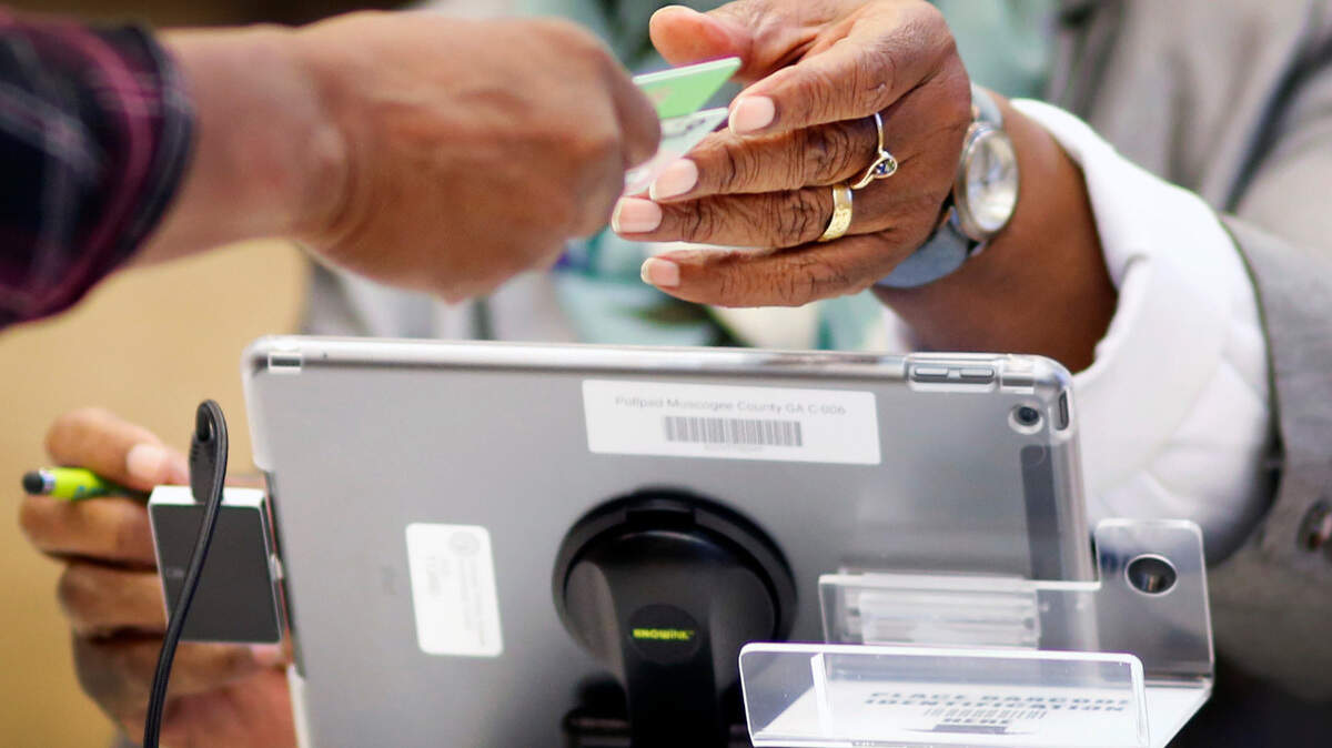 A poll worker in Columbus, Ga., gives a voter a voting card after checking them in Tuesday.