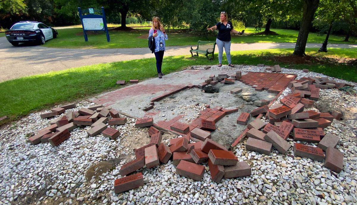 Nichole Smith, left, and Shelly Hall, both from the District Attorney’s Victim-Witness office, survey damage Tuesday morning to the Homicide Brick Memorial in Columbus. 09/20/2022