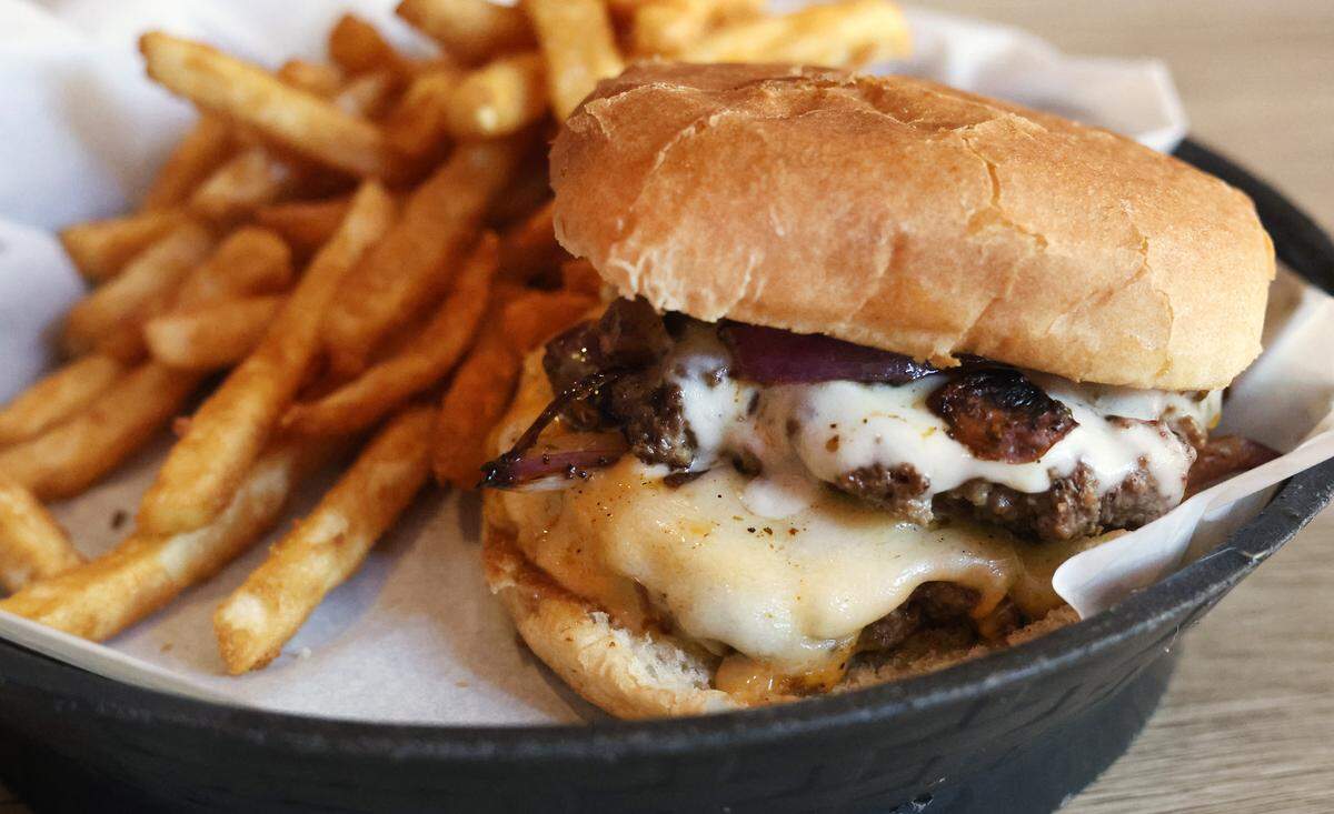 The Cajun Double Burger at Hank’s Bar & Grill, 1037 Broadway in Columbus, comes with two 4-ounce beef patties, melted provolone, American and Swiss cheeses, sauteed mushrooms, red onion and jalapeños, pictured Oct. 21, 2025. It’s served with fries.