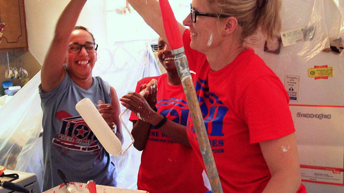 From left, Spec. Lareina Gomez-Lorraine, Capt. Ashley Jefferson-Watts and Capt. Brandy Gainsley celebrate a job well done while painting the kitchen of Izola Bell's Columbus home.