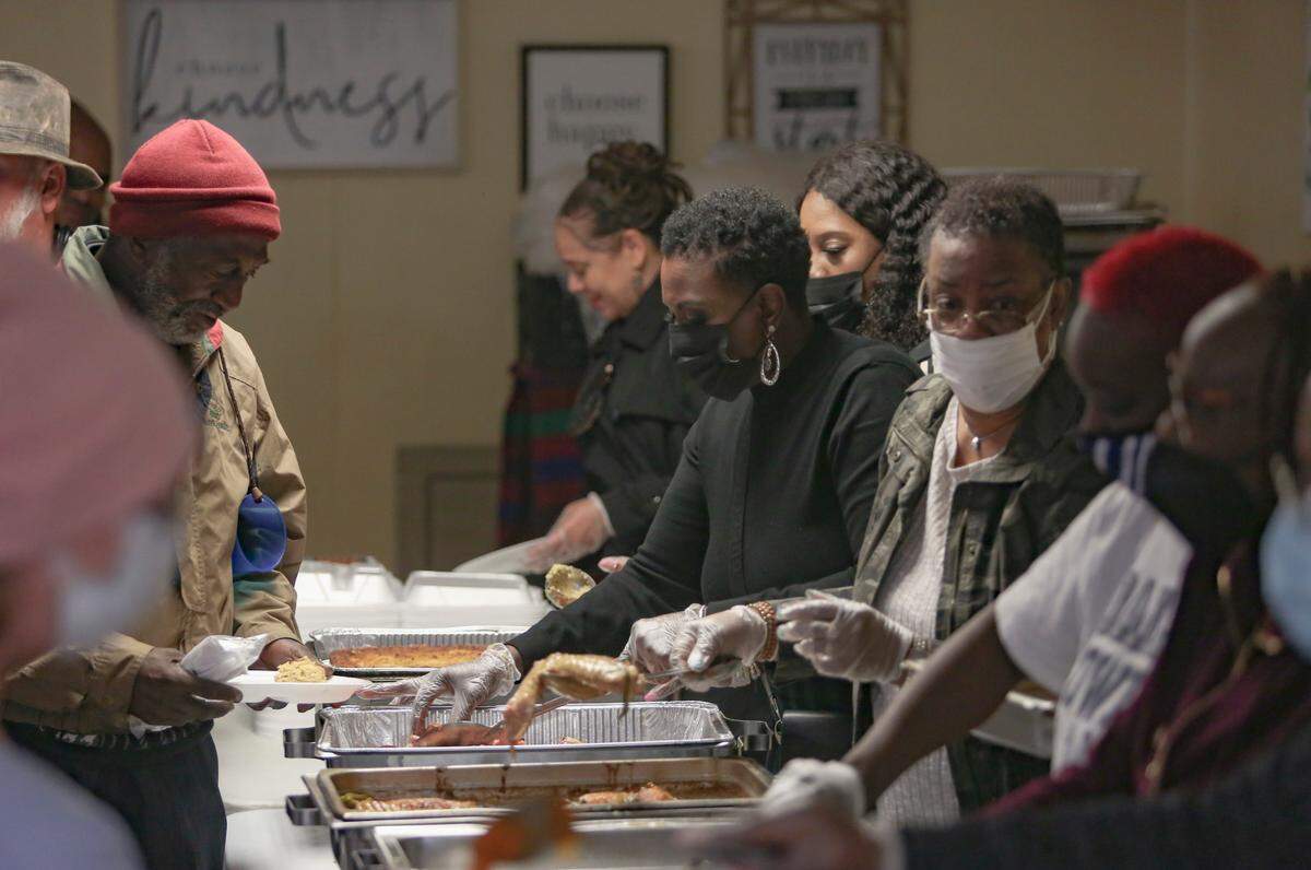 Debbie Crowell serves sweet potatoes to guests at Safehouse Ministries in Columbus, Ga. on Nov. 23, 2021. Her son and former NFL player Isaiah Crowell provides hundreds of Thanksgiving meals for unsheltered people in Columbus every year.