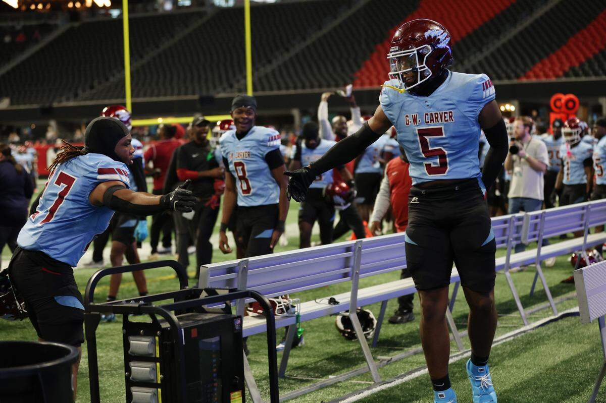 Carver High School senior linebacker Zay Billingsley (5) high-fives a teammate after returning an interception for a touchdown during the Georgia High School Association Class AA state football championship against against Burke County High School on Dec. 17, 2024, at Mercedes-Benz Stadium in Atlanta. The Carver Tigers beat the Burke County Bears 52-14.