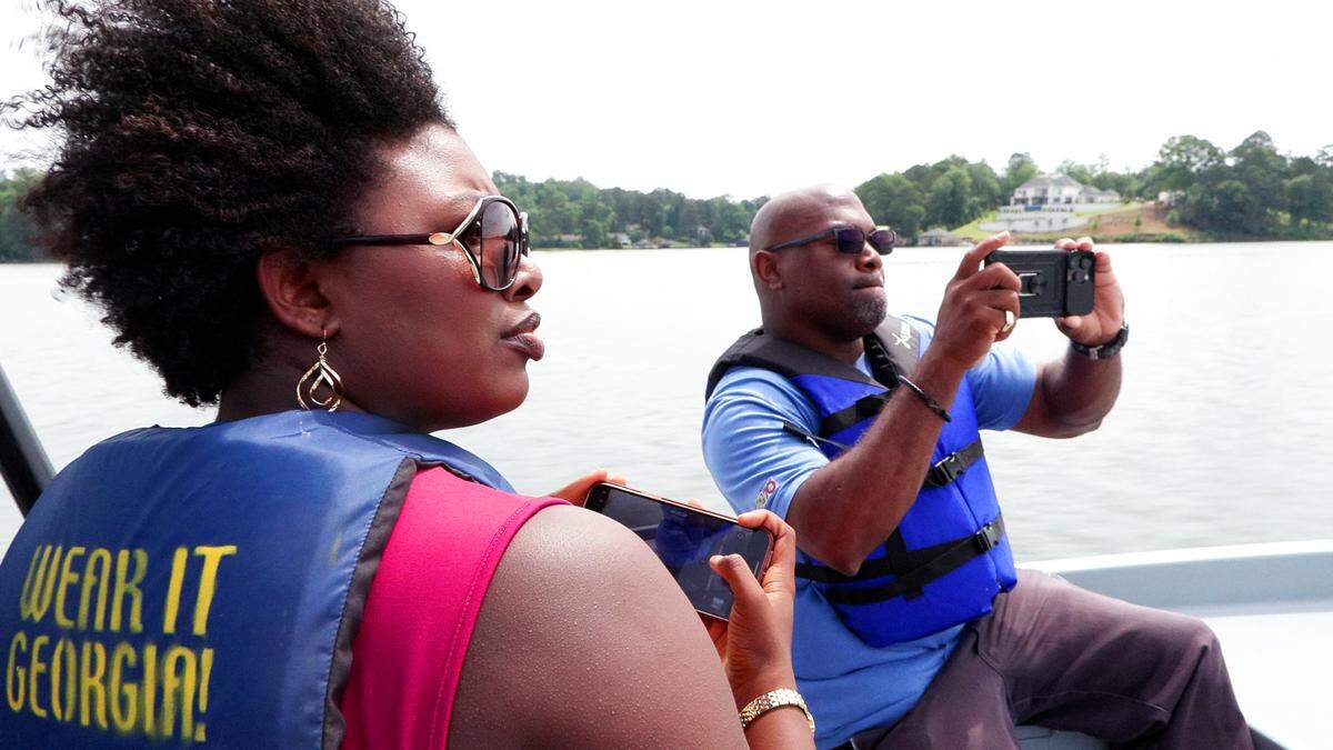 Broadcast journalists Michelle Jennings and Donyel Perry wear life jackets while reporting on a water safety story May 21, 2026, on Lake Oliver in Columbus.