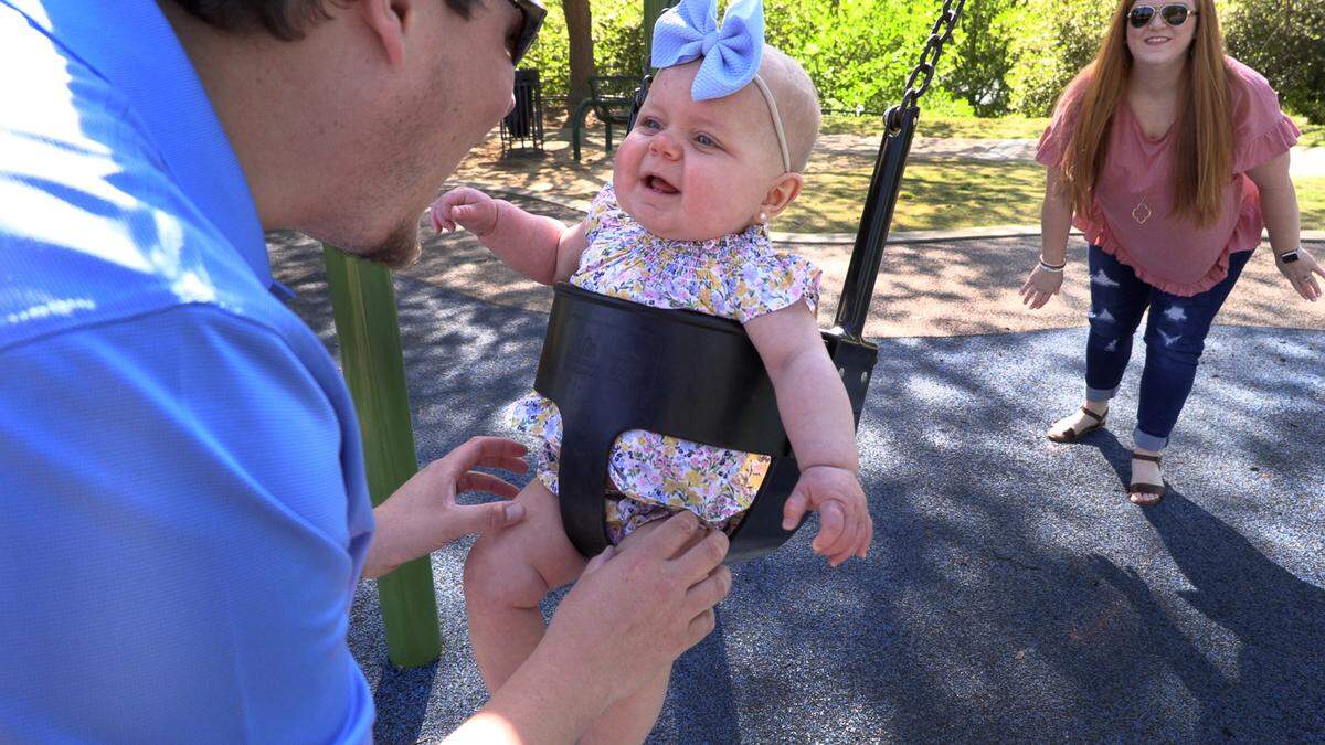 Jeremy and Summer Head play with their daughter Ansley on a swing at a Columbus park.