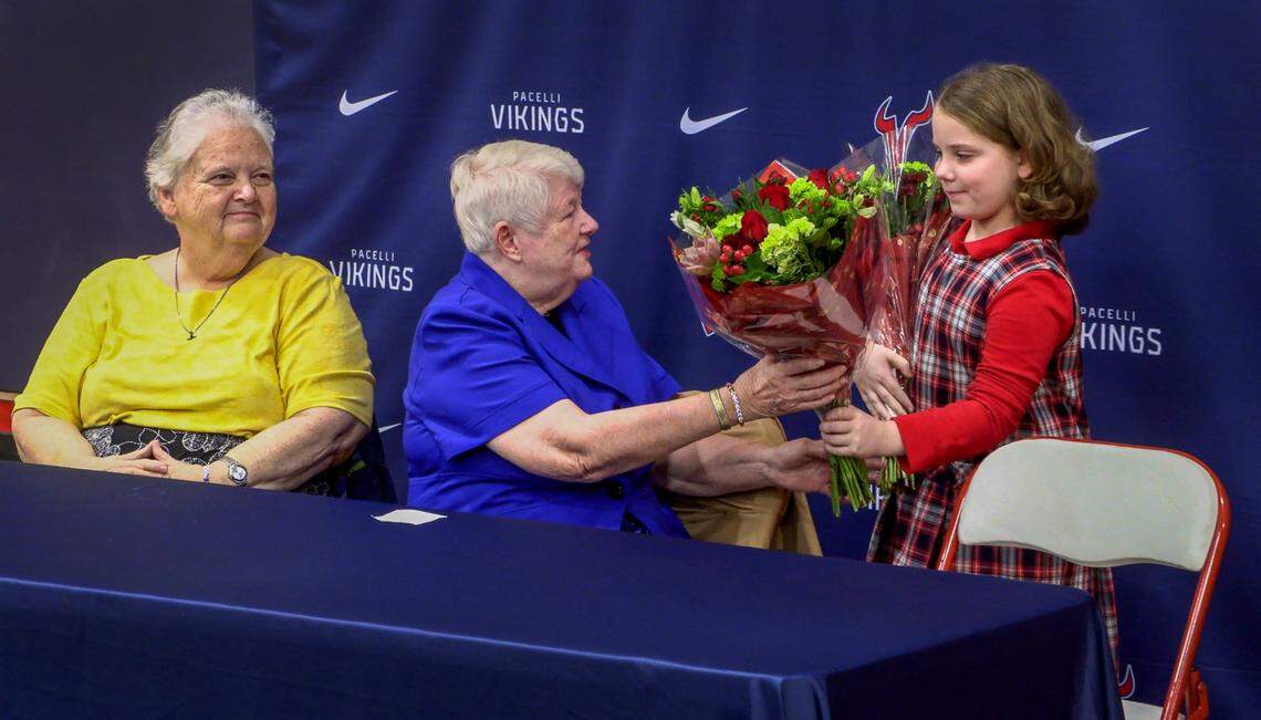 Emma Purdy, a third grader st St. Anne-Pacelli Catholic School in Columbus, gives flowers to Sister Margaret Downing, far left, and Sister Pat Thompson during a ceremony at the school on Dec. 9, 2024, honoring the two, who are retiring.