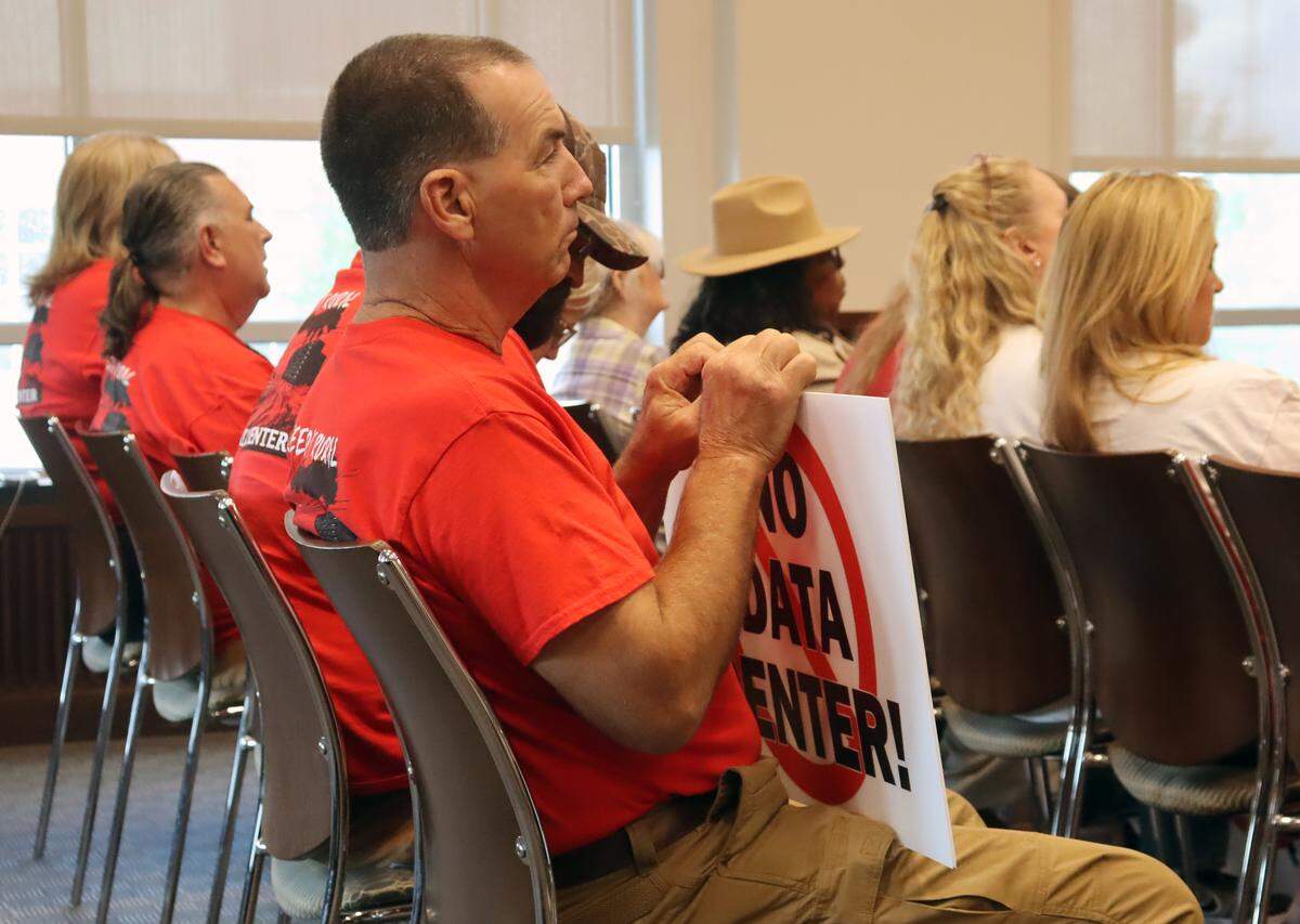 A Columbus resident wears a “Keep It Rural, No Data Center” shirt and holds a “No Data Center” sign at the June 2, 2026, city council meeting in opposition to the proposed Project Ruby hyperscale data center and the proposed technology overlay ordinance.