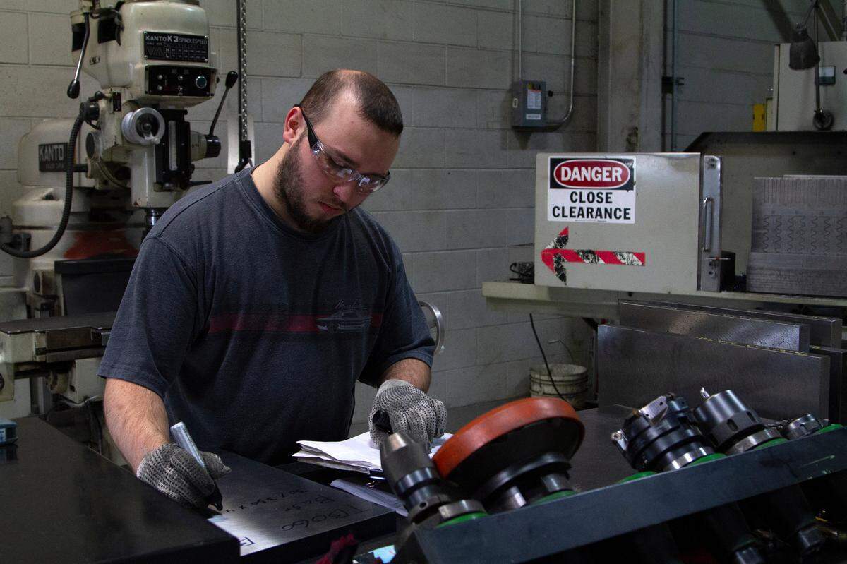Aaron Henderson, a Columbus Technical College student apprenticing at Oneda, writes on a slab of metal after starting a saw on Wednesday, April 10, 2019, in Columbus, Ga. 