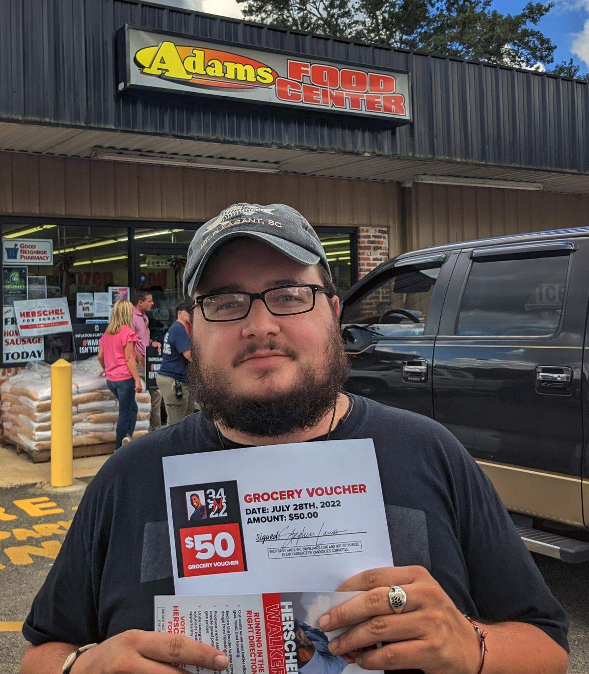 Mathew Ramirez holds up his $50 grocery vouchers from 34N22, a pro-Herschel Walker PAC. Walker is the Republican nominee for U.S. Senate. 07/28/2022