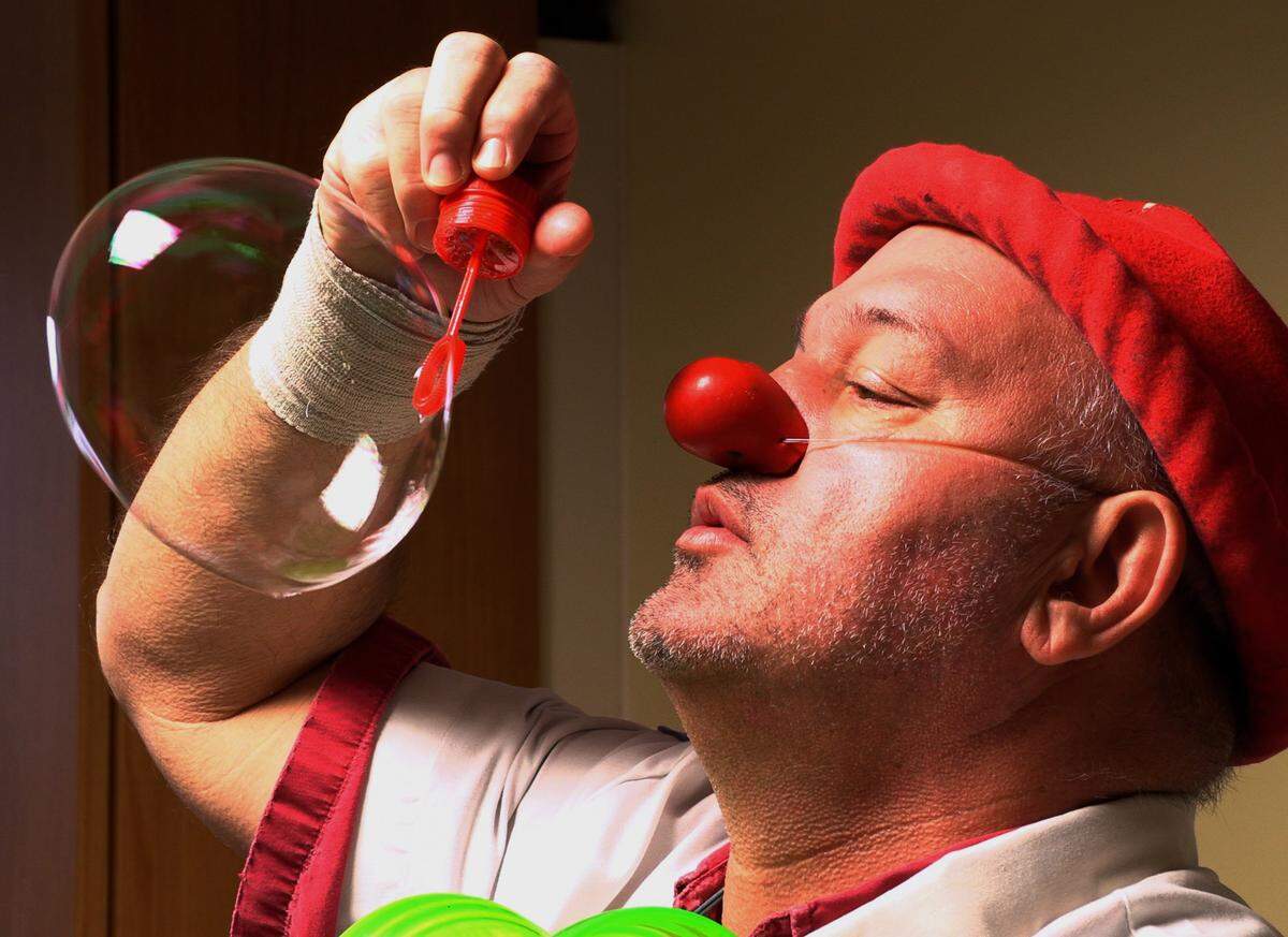 Ron Anglin, whose humorologist character is Dr.Tiny blows a big bubble for patient Oliver White,3, Thursday at Piedmont Columbus Regional Hospital in Columbus, Georgia, Settimi is with HA!, Humorology Atlanta. It’s an Atlanta-based nonprofit, that deploys professional “Clown Doctors” to entertain patients and families at children’s hospitals, helping relieve discomfort and distress.