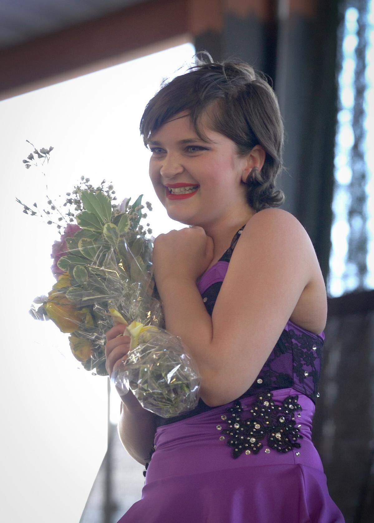Lexy McRae holds a bouquet on-stage after finishing her first dance recital, on May 29, 2021, since an osteosarcoma diagnosis, at the Harley Davidson store in Columbus, Ga.