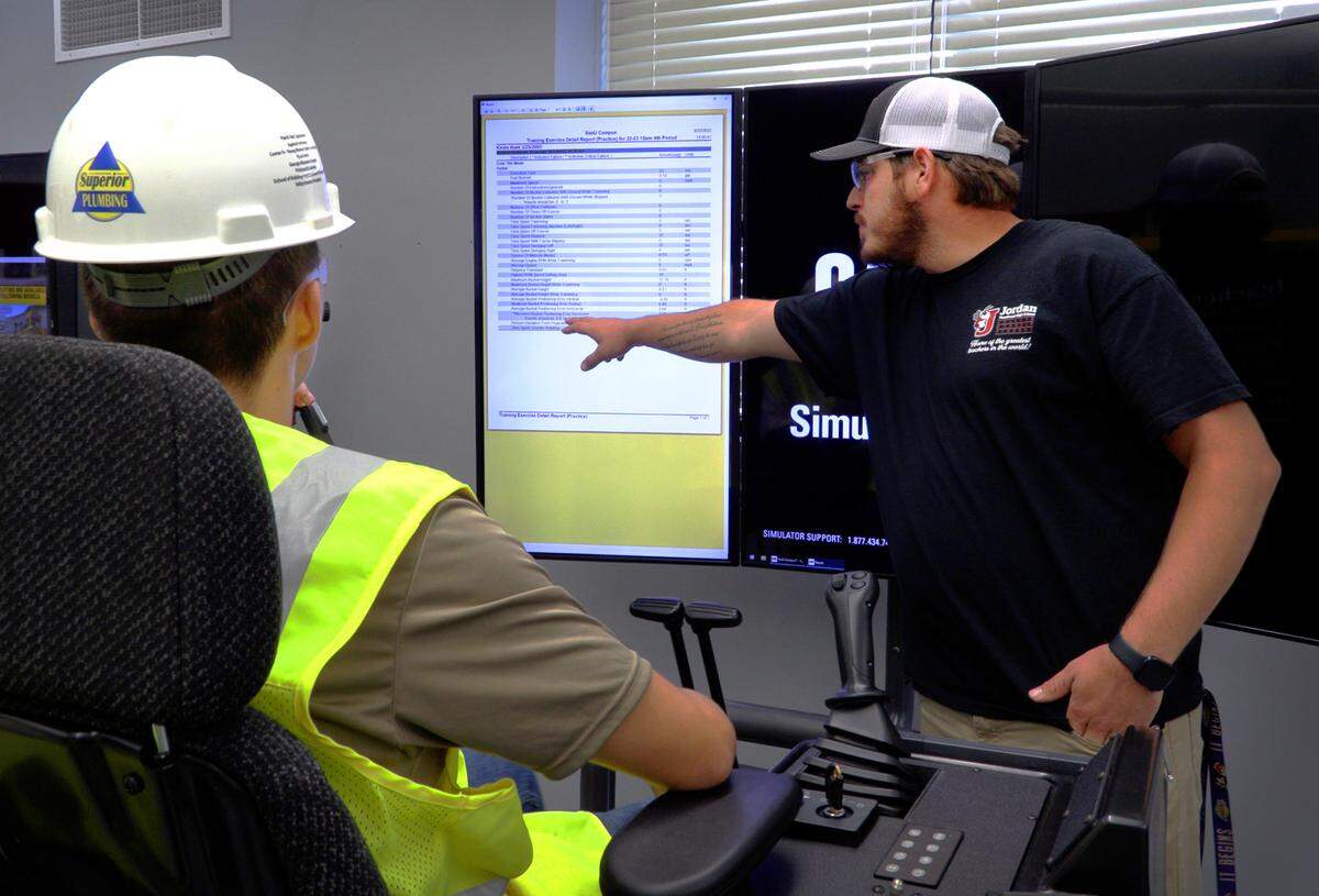 Jimmy Napier, right, a teacher at Jordan Vocational High School, shows Kevin Hunt, 17, a junior at the school, the score he received while working on one of the CAT Simulators in the school’s Heavy Equipment Operator Training Program. 09/23/2022