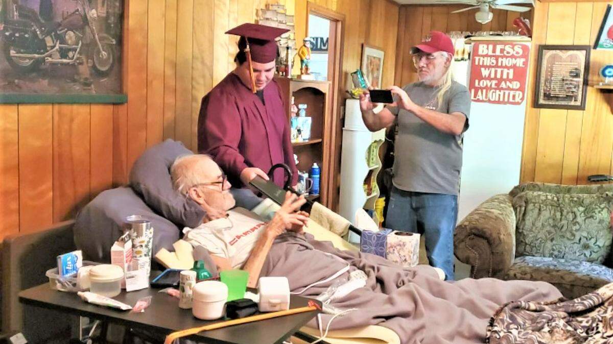 Michael Bowden shows his father, Mike Bowden Sr., the diploma he received during the special graduation ceremony the Russell County High School administration conducted at the Bowden family’s home in Seale on April 25, 2022, because Mike’s cancer battle prevented him from attending the official ceremony. Mike died two weeks later.