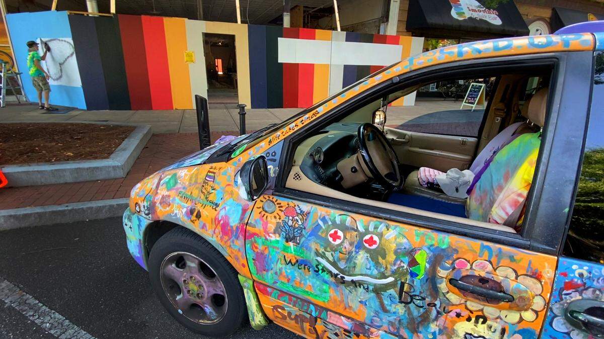 Ralph Frank paints a mural in downtown Columbus as his art van is parked nearby in 2021.