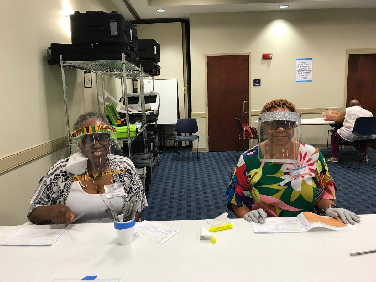 Assistant polling manager abbey Davis, left, and polling clerk Judy Smith, right, sport homemade masks made by Davis for Election Day at Precinct 121.