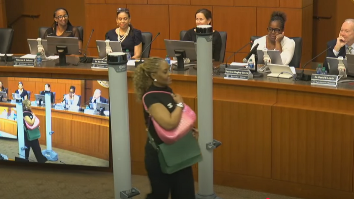 In this screenshot from the Muscogee County School District’s video of its July 21, 2025, board meeting, MCSD communications director Kimberly Wright demonstrates the proper way to walk through one of the weapon detectors MCSD plans to install at all of its middle and high schools this year.