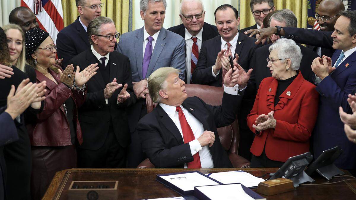 President Donald Trump hands off a pen after he signed the First Step Act and the Juvenile Justice Reform Act in the Oval Office of the White House in Washington, D.C., on Dec. 21.